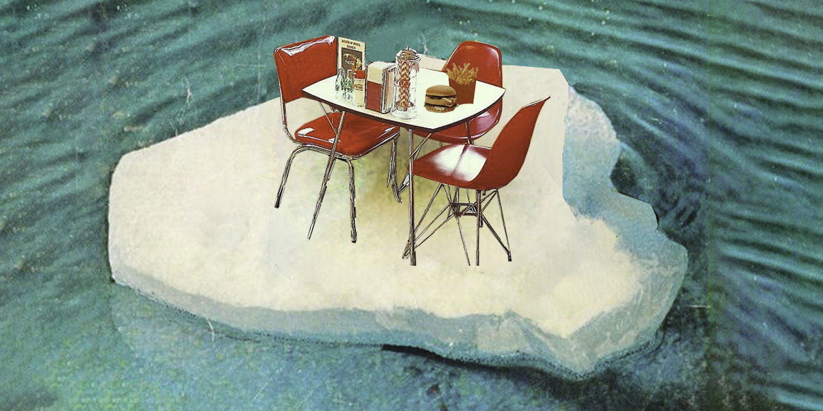 A table and Coca-Cola chairs sit on a floating chunk of ice in the ocean. The table is set with burgers, fries, napkins, and a flag.