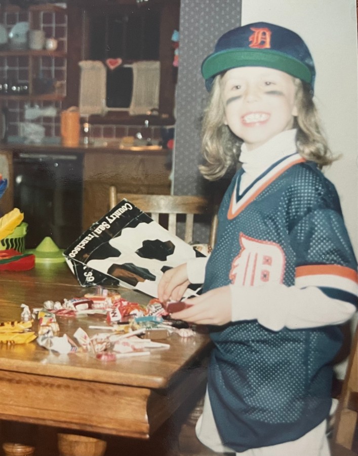 Riese as a young child in a Detroit Tigers uniform for Halloween, counting her candy