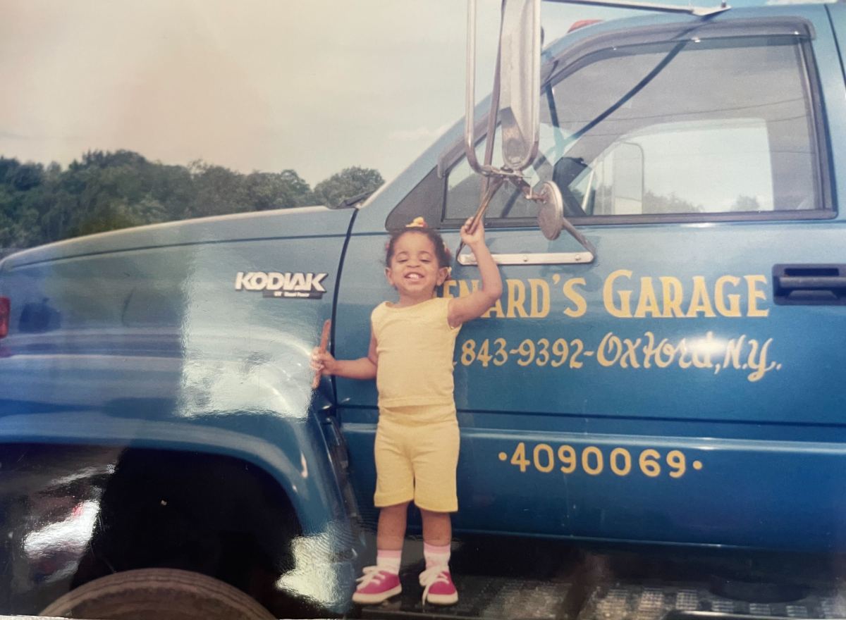 Dani stands on the runner of a blue truck