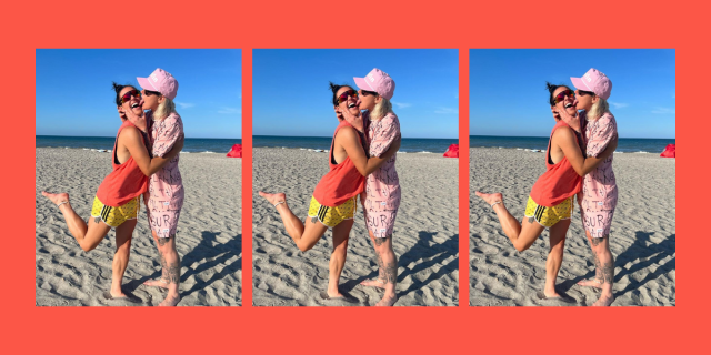 Ashlyn Harris wears a pink shirt and pink shorts and pink hat on the beach while holding and licking the face of Ali Krieger who is wearing a red rank and yellow shorts.