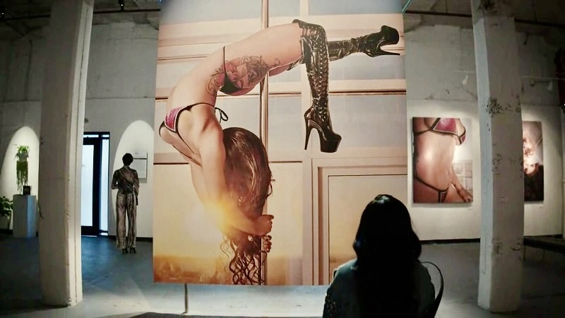 A photograph of Mercedes, dancing upside down on a pool in her floss, is hung in an art gallery.