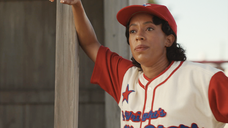 Esther leans against the dugout. 