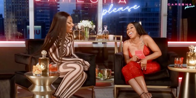 Megan thee stallion Yung Miami interview: Megan Thee Stallion and Yung Miami laugh together, Meg's in a black and white stripped body suit that covers to her toes, and Yung Miami is in a red dress