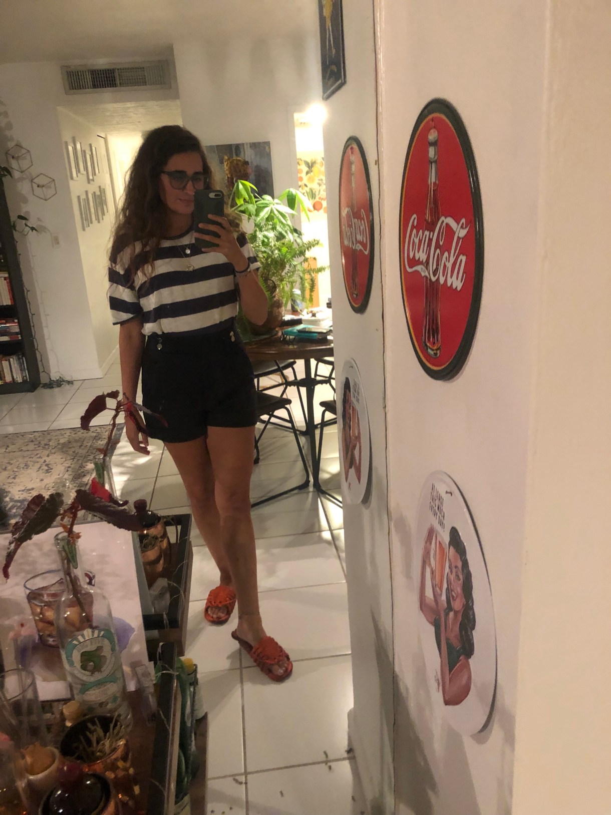 Kayla Kumari Upadhyaya wears a blue and white striped tee with blue sailor shorts and lobster-shaped flipflops