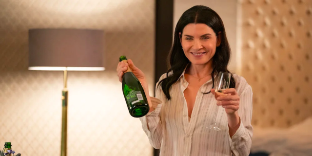 Julianna Margulies holds a bottle of champagne and an empty glass on The Morning Show