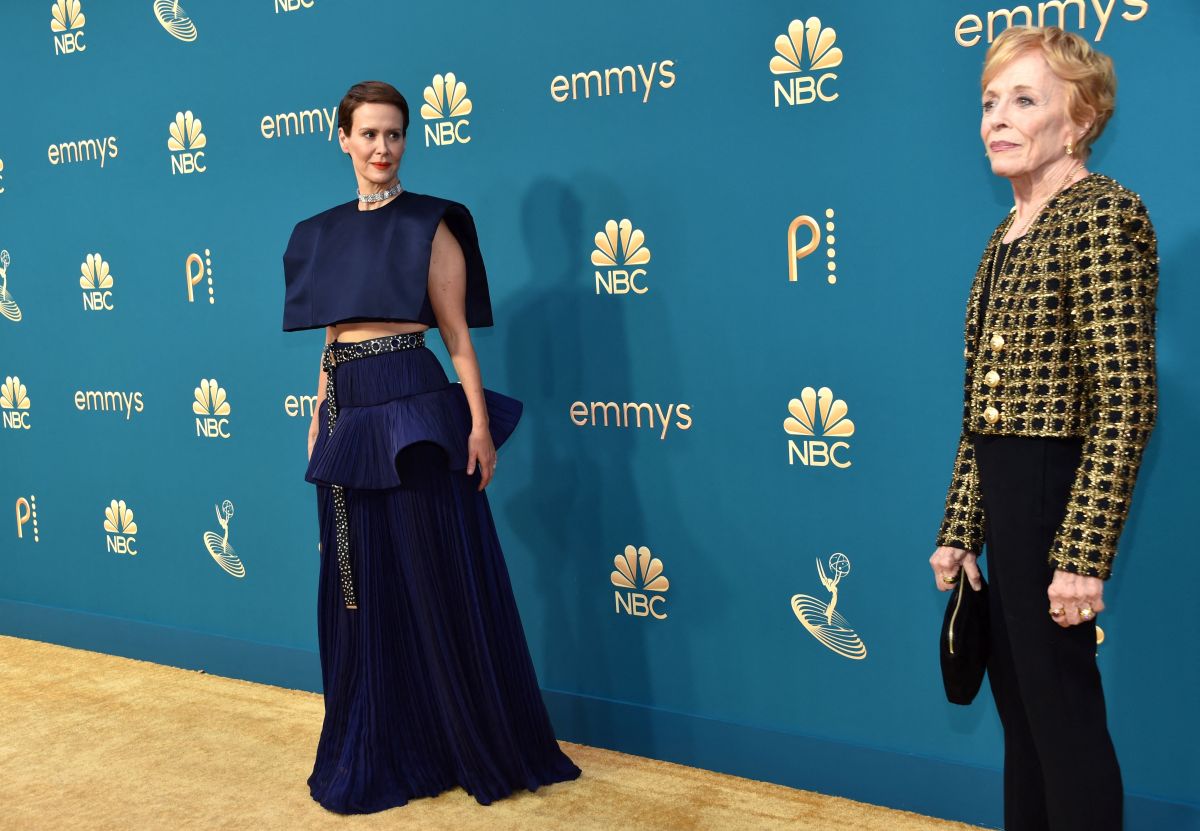 Sarah Paulson in a navy blue dress looks lovingly at Holland Taylor in a gold patterned jacket and black pants