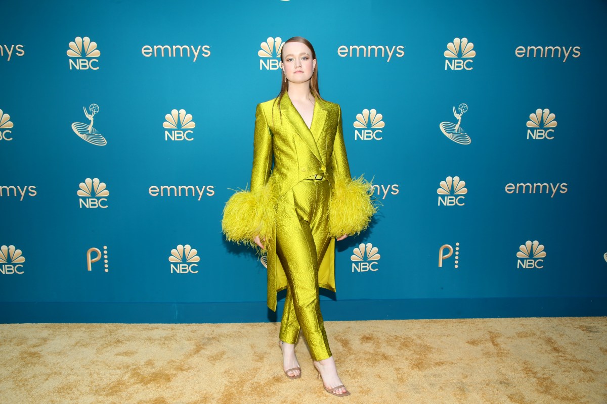 Liv Hewson in a lime green suit with lime green faux fur cuffs that go halfway up her arm.