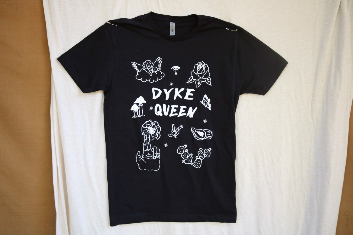black t-shirt that reads DYKE QUEEN in white letters with line drawings in white surrounding the text