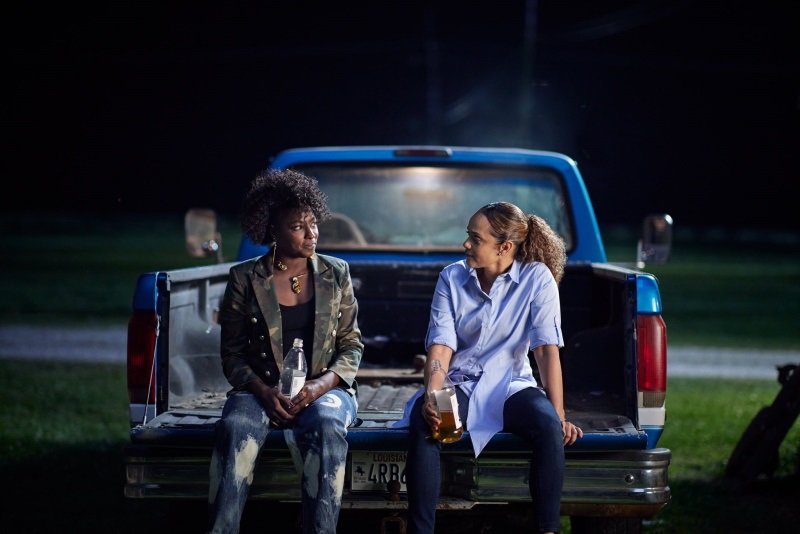 Nova and Billie sit on the back of an old blue pickup truck, sipping out of 40 oz bottles, talking about their day.