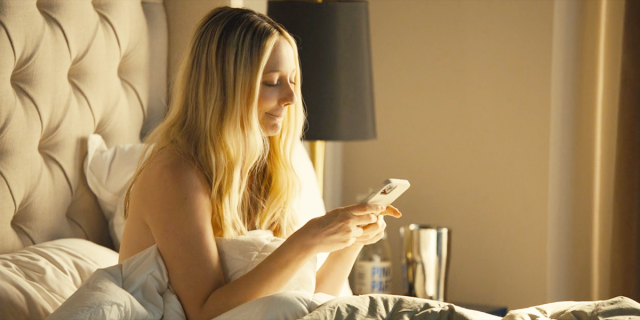 Judy Greer as Bree on her phone in bed in Reboot on Hulu