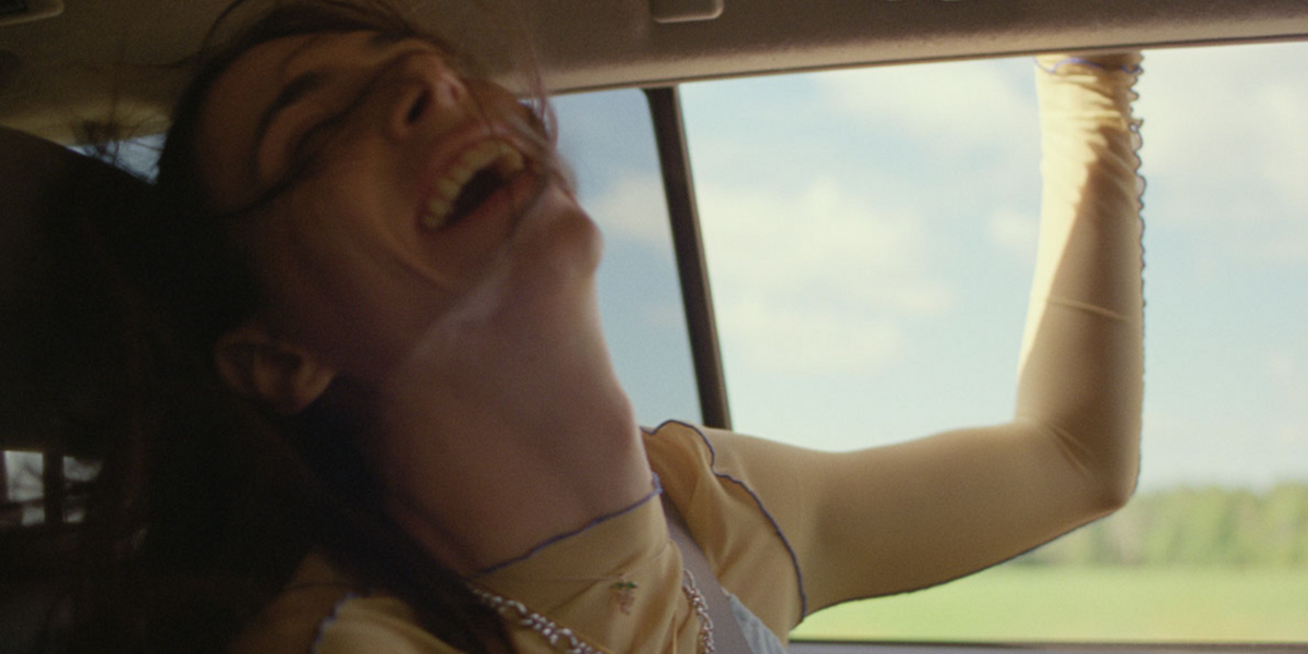 Renatta in the film "Something You Said Last Night" laughs while riding in a car with the windows down