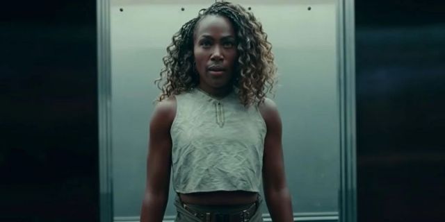 Kayla Watts played by DeWanda Wise in Jurassic World Dominion wears a cropped gray tanktop while standing in an elevator.