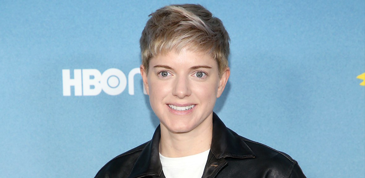 Mae Martin in front of an HBO background on the red carpet of the Hacks premiere 