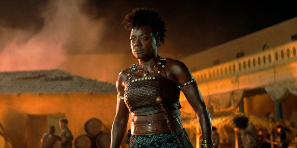 Viola Davis dressed as a Dahomey warrior in front of an orange sky in The Woman King