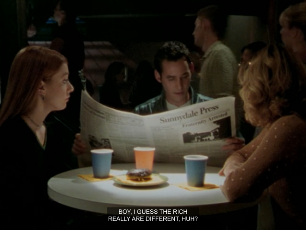 Willow, Xander and Buffy sitting around a table in the Bronze. Xander is reading a paper and saying “boy, I guess the rich really are different, huh!”