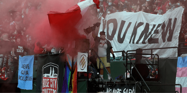 Protestors at a soccer game in Portland use megaphones and red paint spray