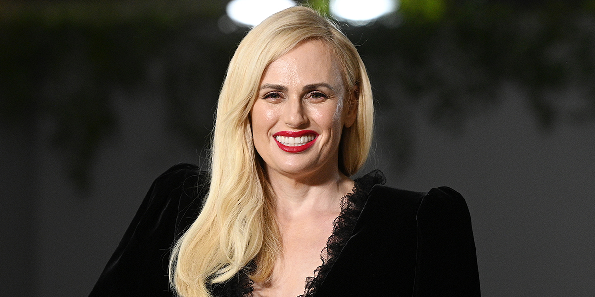 Rebel Wilson smiling in a black dress on the red carpet