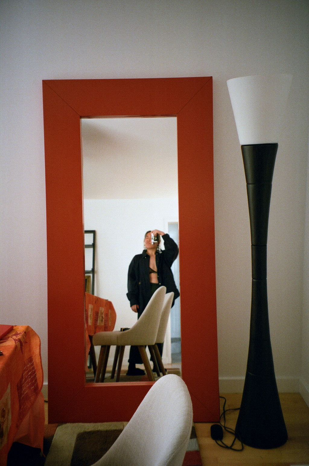 a photo of Julie, a young Asian woman, from far away, artfully taken in a full length mirror