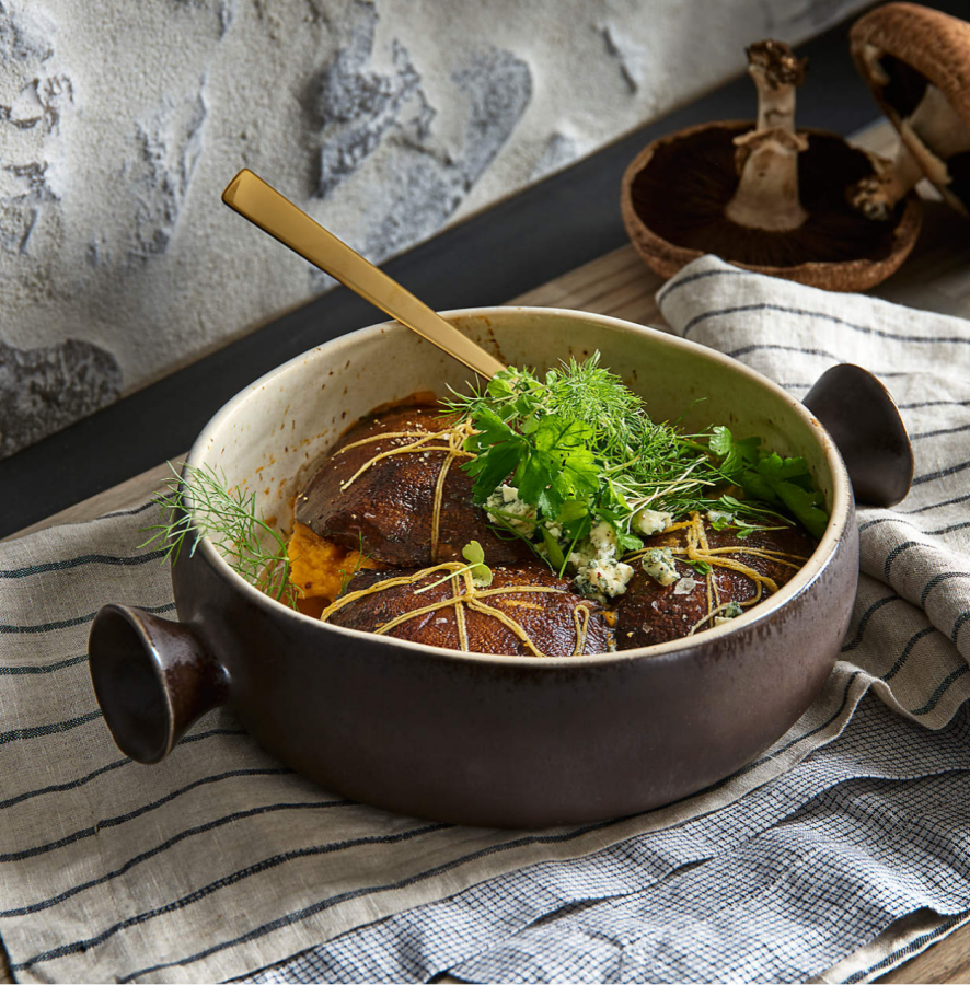 A brown serving bowl with handles with a speckled interior