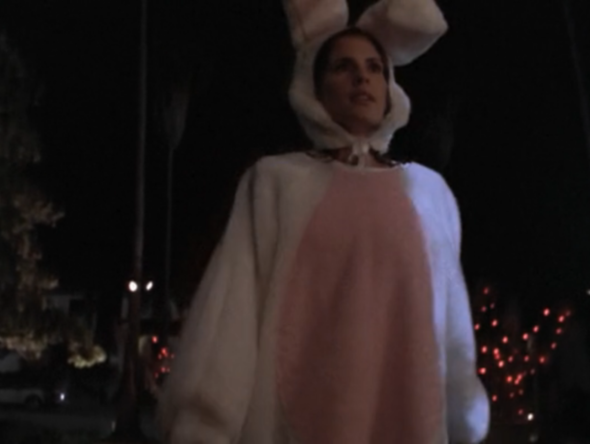 Anya walking up to a house in the dark, wearing a giant bunny suit with a pink belly