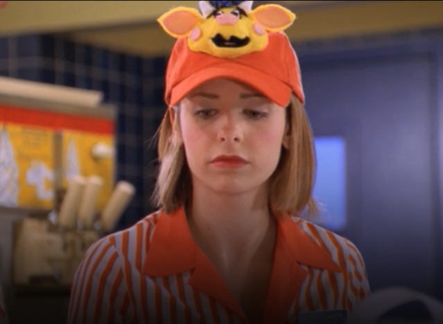 Buffy wearing a fast food uniform, with a cow on her hat