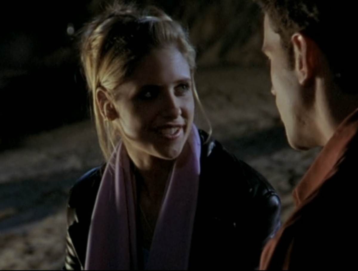 Buffy at a party in the dark, smiling at a guy who doesn't deserve her