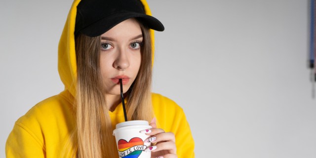 girl in a yellow hoodie drinking a hot cup with a cold straw