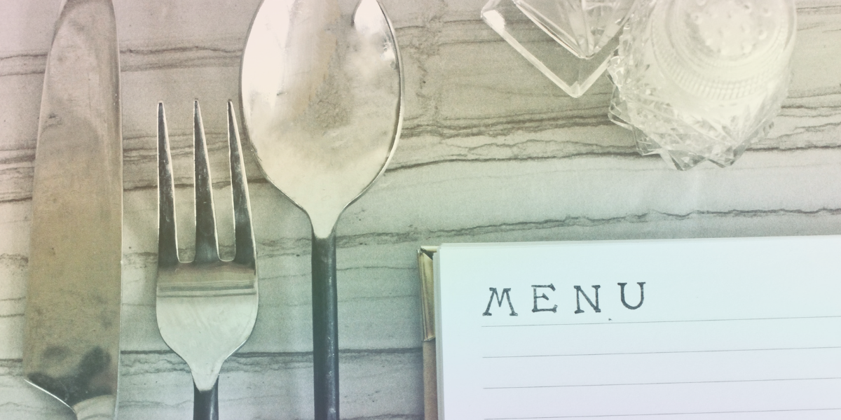 overhead table: knife, fork, spoon, salt shakers, and blank menu template, all set on a table
