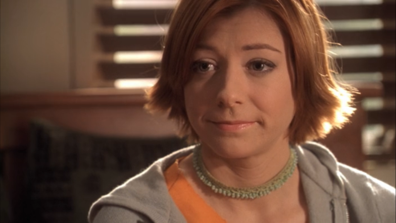 Willow from Buffy The Vampire Slayer has her red hair flipped to the side and is making a solemn face