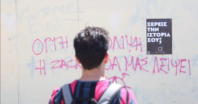 Queer Athens team members puts up a poster for the project in Athens. The poster says, ‘Do you know your history?’