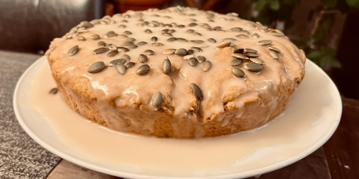 A glazed olive oil cake with pumpkin seeds on it