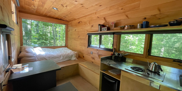 A Getaway House cabin, which looks like a small room with a bed, kitchen, and wood panel walls. It also has lots of windows.
