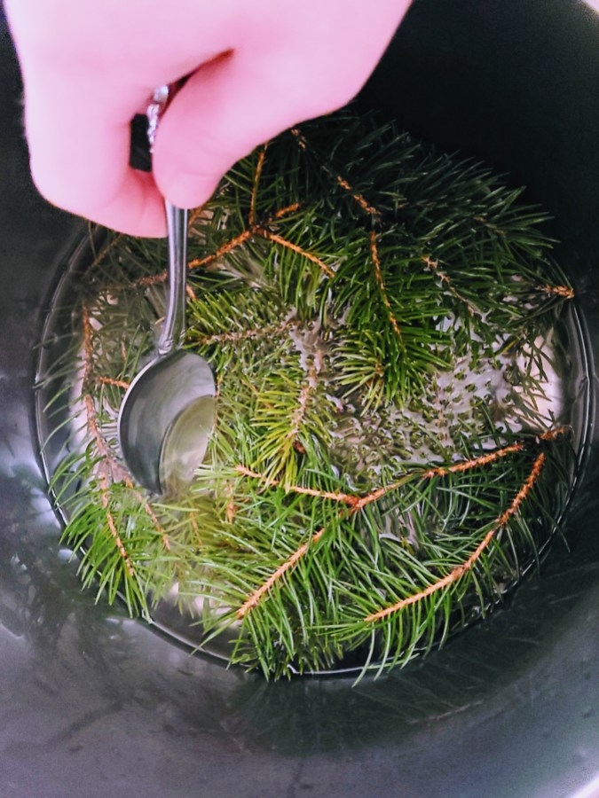 several branches in a pot of simple syrup which nico is stirring