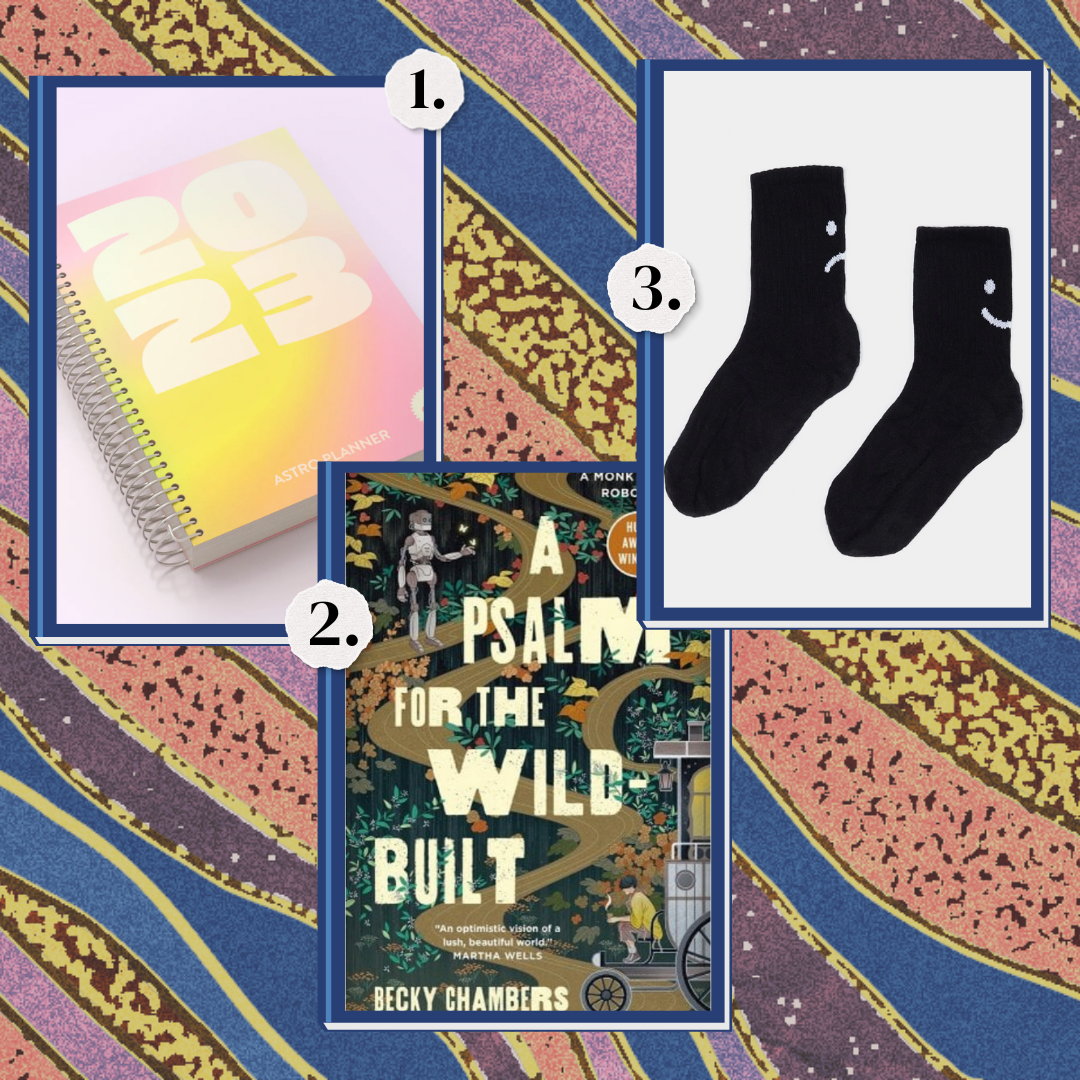 1. A 2023 planner. 2. A Psalm for the Wild Built by Becky Chambers. 3. A pair of black socks with sad faces on them.