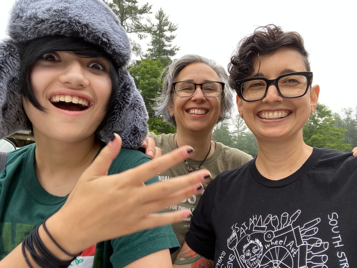 In a recent photo. Mia and Tracy smile with their teenage kid outside in a forest.