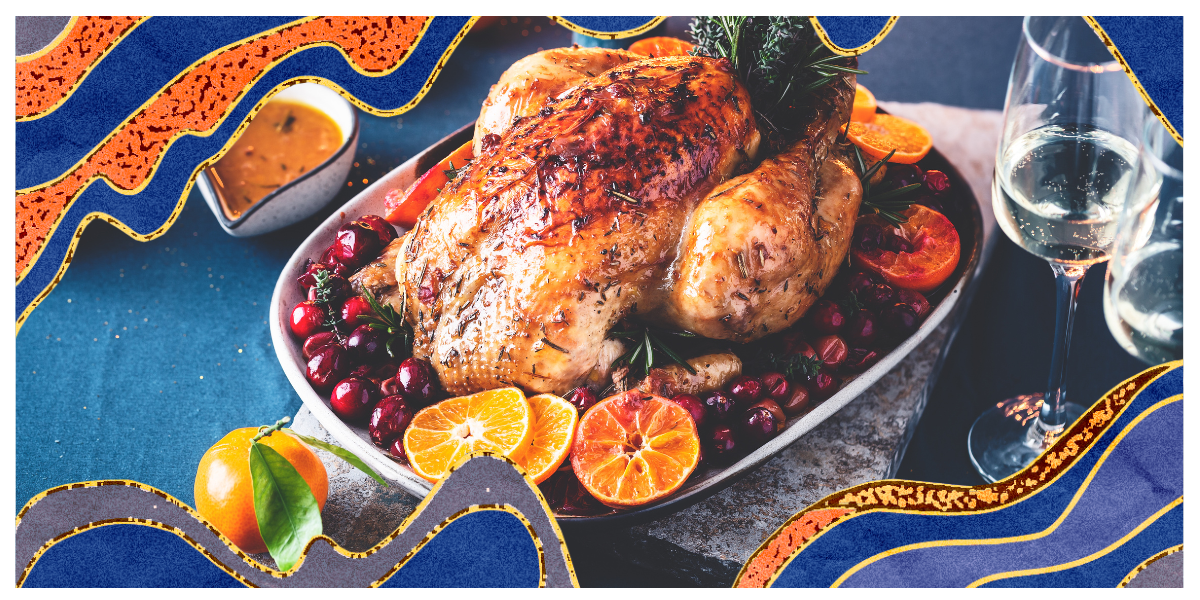 a roasted turkey with cranberry and orange on a table.