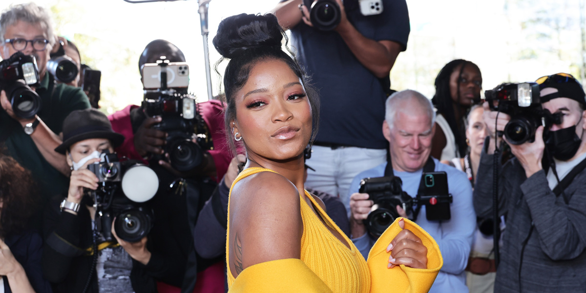 KeKe Palmer is in a yellow gown on a red carpet, surrounded by Paparazzi, and she's making a kissy face at the camera