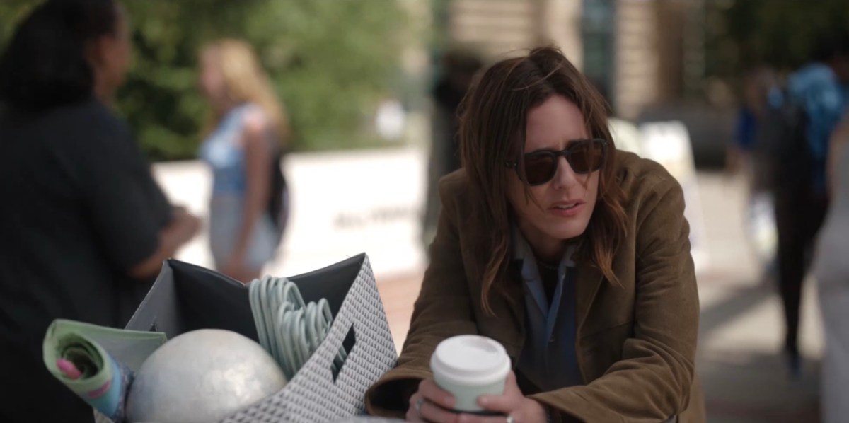 Shane looking surly with a coffee cup leaning on a travel bucket