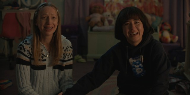 Maya Erskine and Anna Konkle hold hands and laugh cry looking up at a screen in the final moments of Pen15.