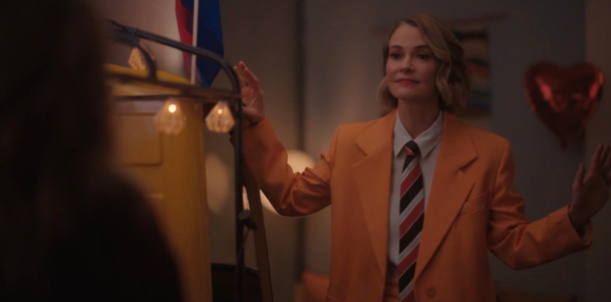 Alice in her suit and a big yellow blazer and tie, looking goofy