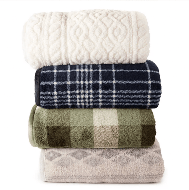 a stack of four blankets: one white, one blue with white stripes, one green check and one beige pattern