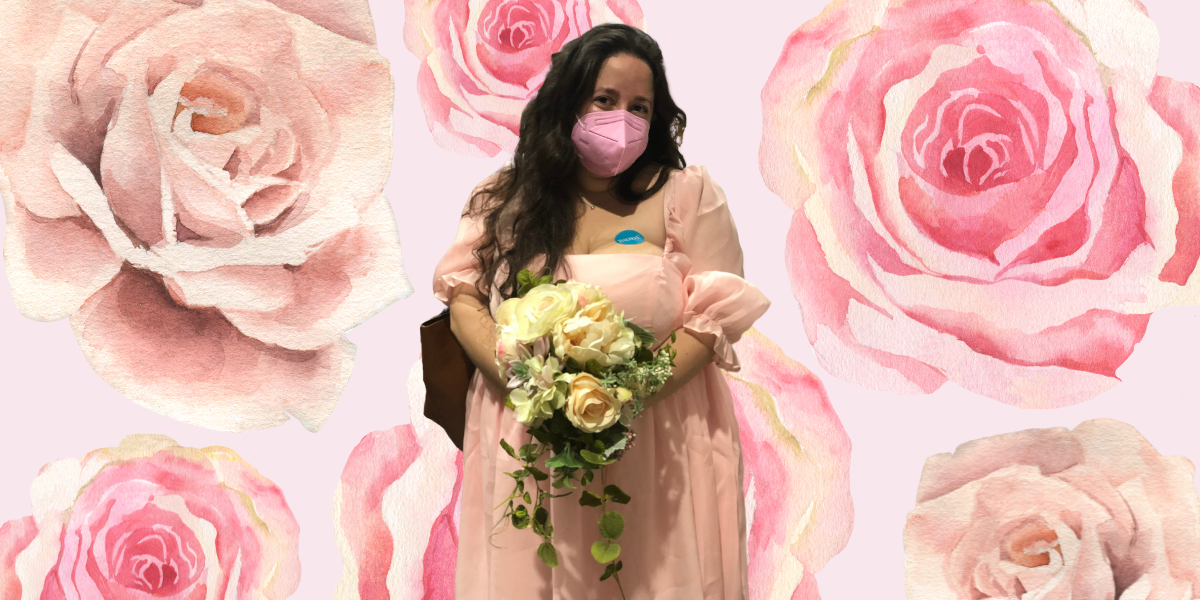 Light and dark pink roses are against a pale pink background. Vanessa, a white person with long, brown hair who's wearing a pink dress with ruffled sleeves and a pink KN95 mask, stands in the center holding a bouquet of white and pink roses.