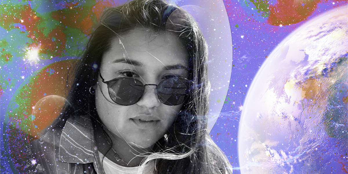 a photo of Em is set in black and white against a colorful spacey background. Em is a mixed race Asian human with long dark hair, wearing sunglasses and a jacket in this photo, looking a little windswept. They have a serious expression.