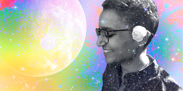 Himani, a South Asian woman with short wavy hair and glasses smiles with a flower in her ear. She is set in black and white against a spacey, colorful background.