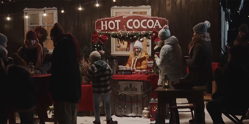 A teenage girl with a fancy stand selling hot cocoa in the snow
