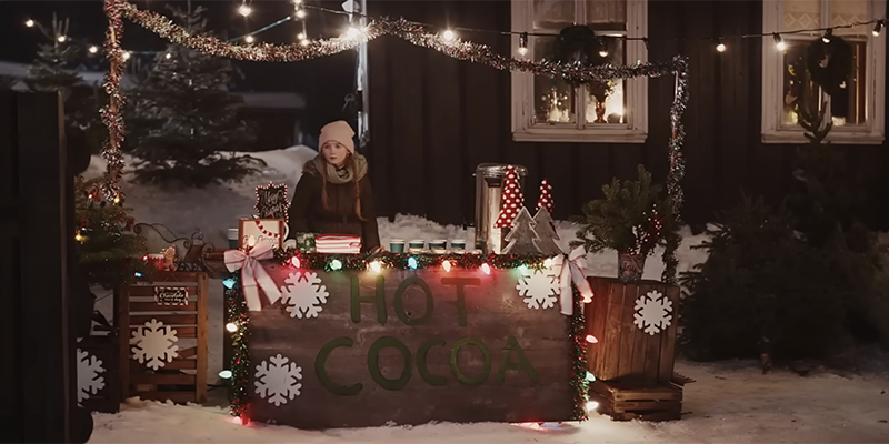 A teenage girl with no line at her hot cocoa stand