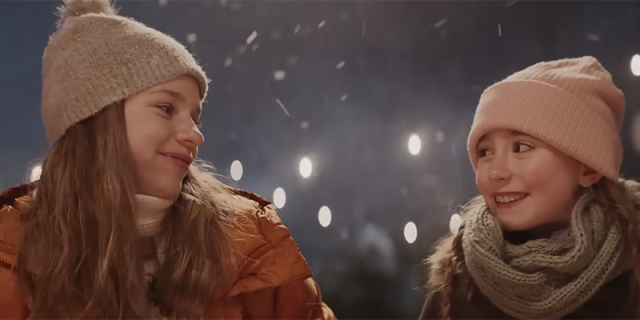 Two teenage girls smiling at each other in the snow