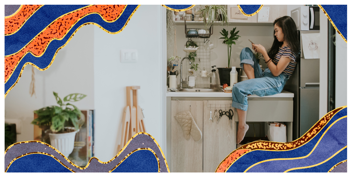 A woman sits on her kitchen counter, reading something on her phone.