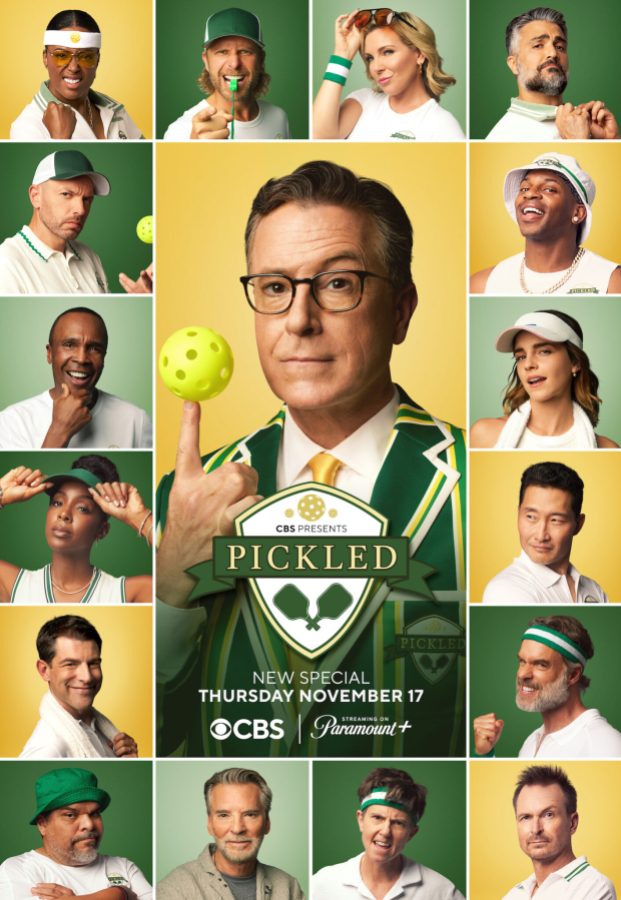 16 celebrities in pickleball gear surround Stephen Colbert who is wearing a green suit and holding a pickleball