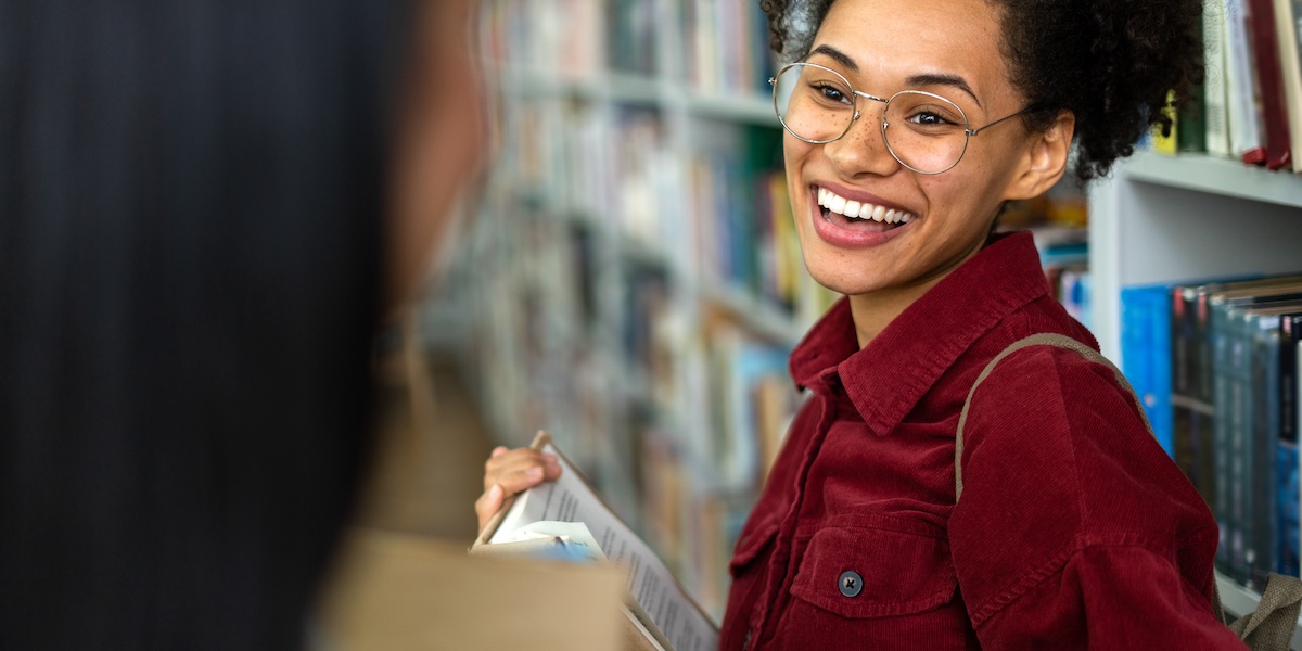 girl smiling in the library at who she ismeeting